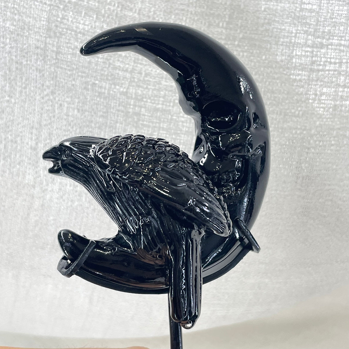 a hand-carved black obsidian raven perched on a crescent skull moon.