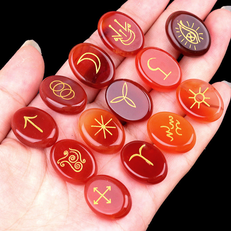 Hand holding red stones with yellow symbols against a black background