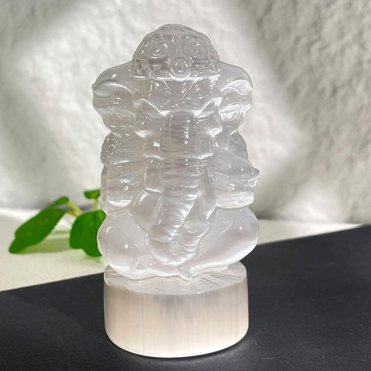  A hand-carved translucent white selenite crystal statue of the Hindu elephant god Ganesha, glowing with a natural pearly luster.