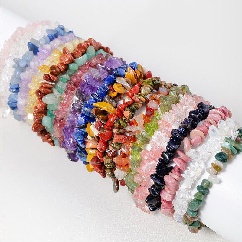 A stack of many different colorful crystal chip bracelets worn on a display stand.