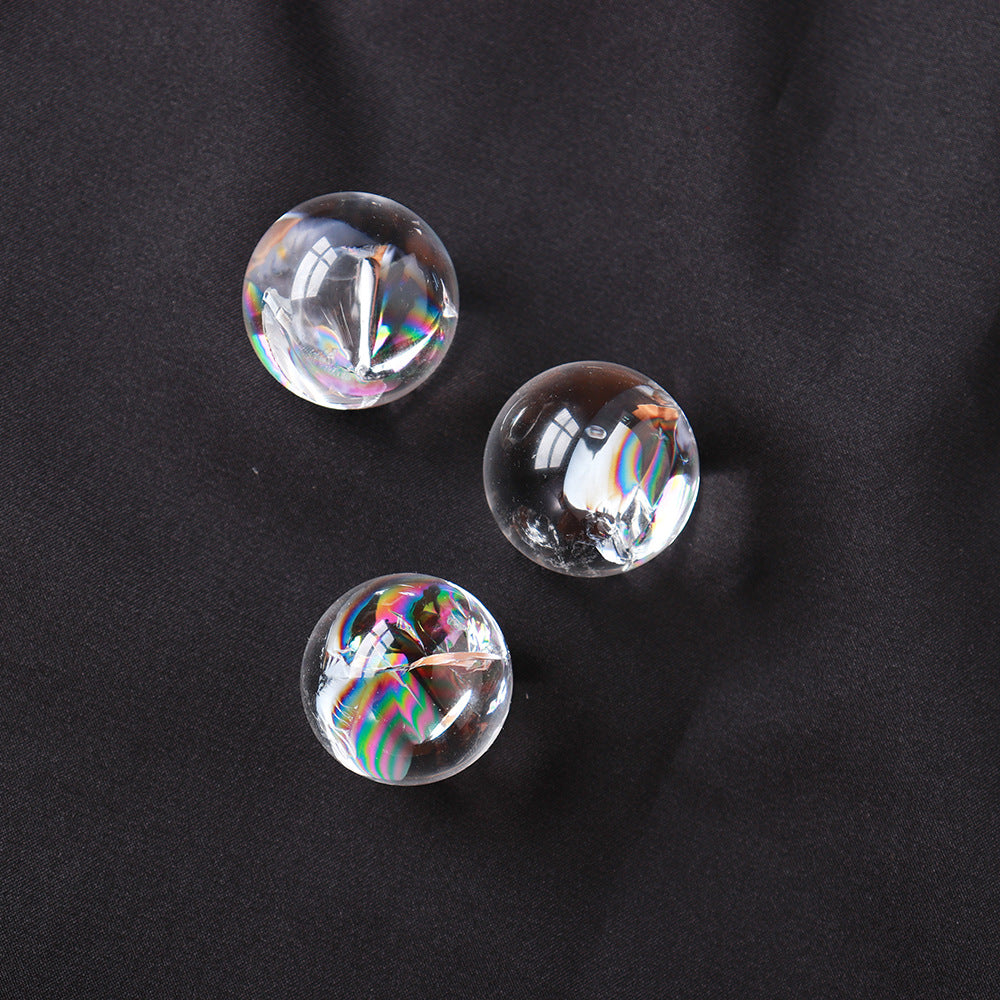 Three mini rainbow clear quartz spheres showing their vibrant rainbow inclusions on a black background