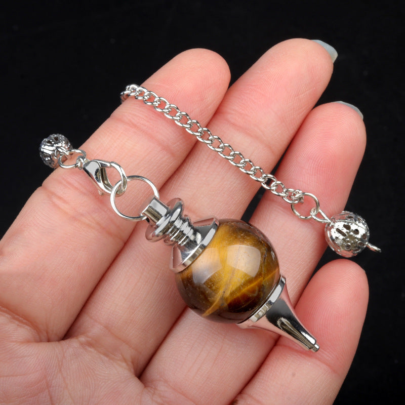 Hand holding a polished Tiger's Eye crystal pendulum with a silver chain
