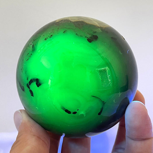 Volcanic agate sphere glowing a vibrant electric green under UV light